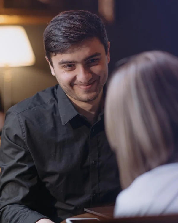 A conversation across a café table under a warm lamp